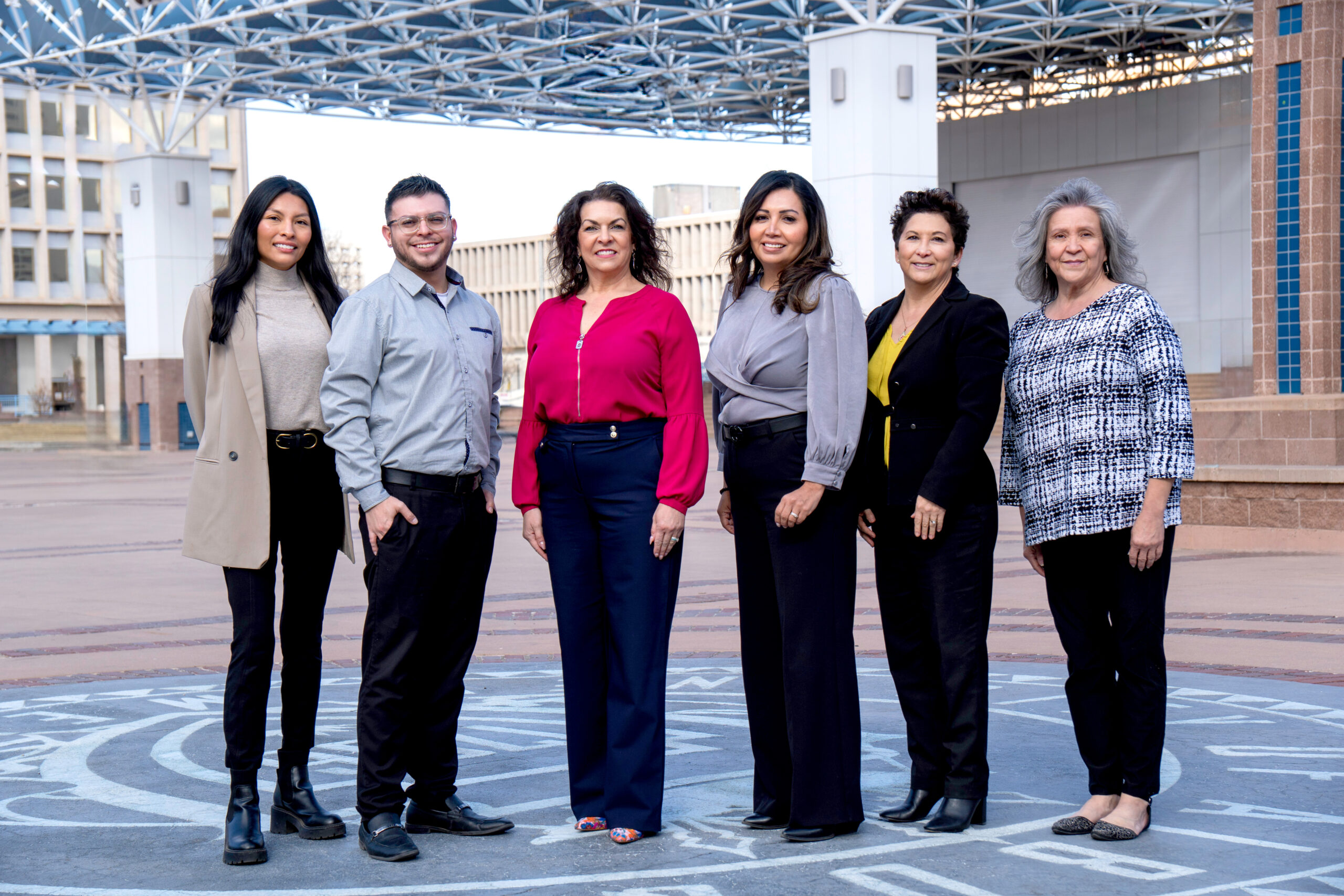C&T Team Adj sm Six people standing in civic plaza, dressed in business attire, with the recognizable PNC Building and large modern pavilion structure in the background.